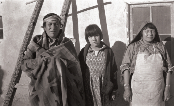 Two adults and one child pose steely-eyed in a sepia toned photograph