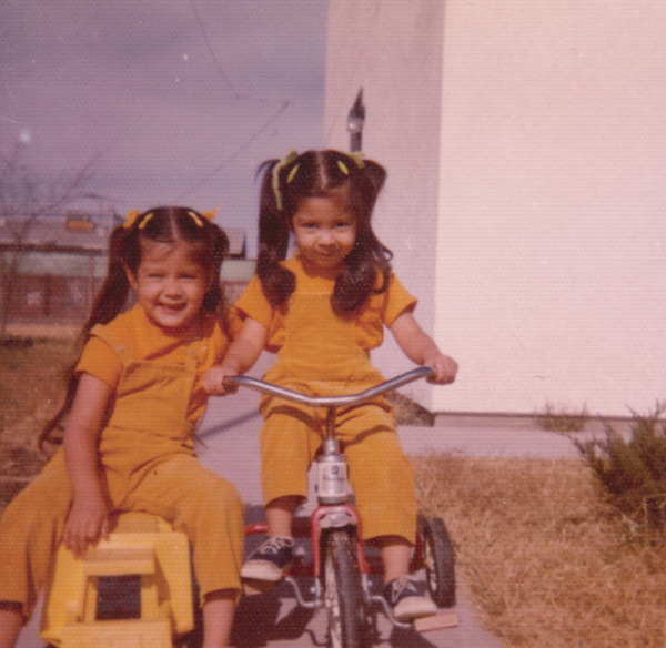 color photo of two girls on tricycles in matching yellow outfits in the mid 70s