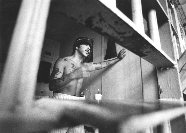 Black-and-white photograph of a prisoner with a knit cap in their cell