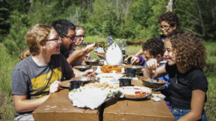 Diverse group of older children eating outdoors at a picnic table