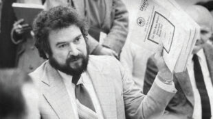 black and white, historic photograph of a politician holding up a stack of papers