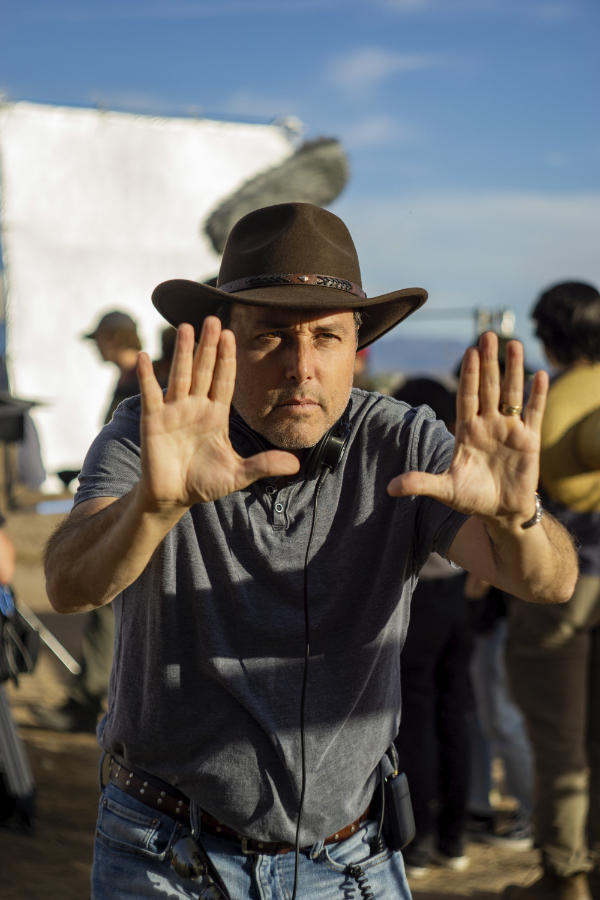 Color portrait of a caucasian man with a leather cowboy hat. His hands are up creating a frame with his hands