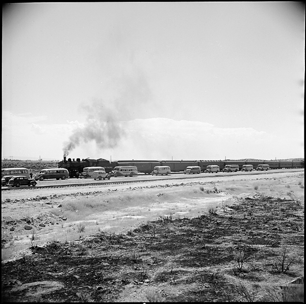 vintage photo a bleak landscape with a train advancing behind a line of cars in traffic