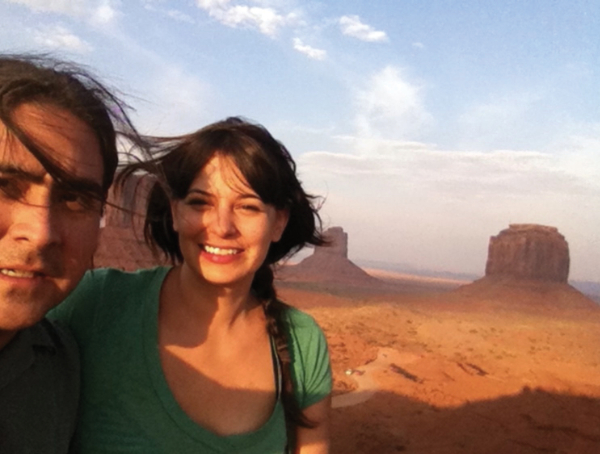 color photo of man and a woman in front of mesa formations of monument valley