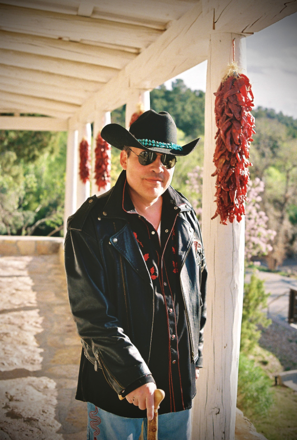 Color photo of man with black hat on a typically New Mexico portal or porch