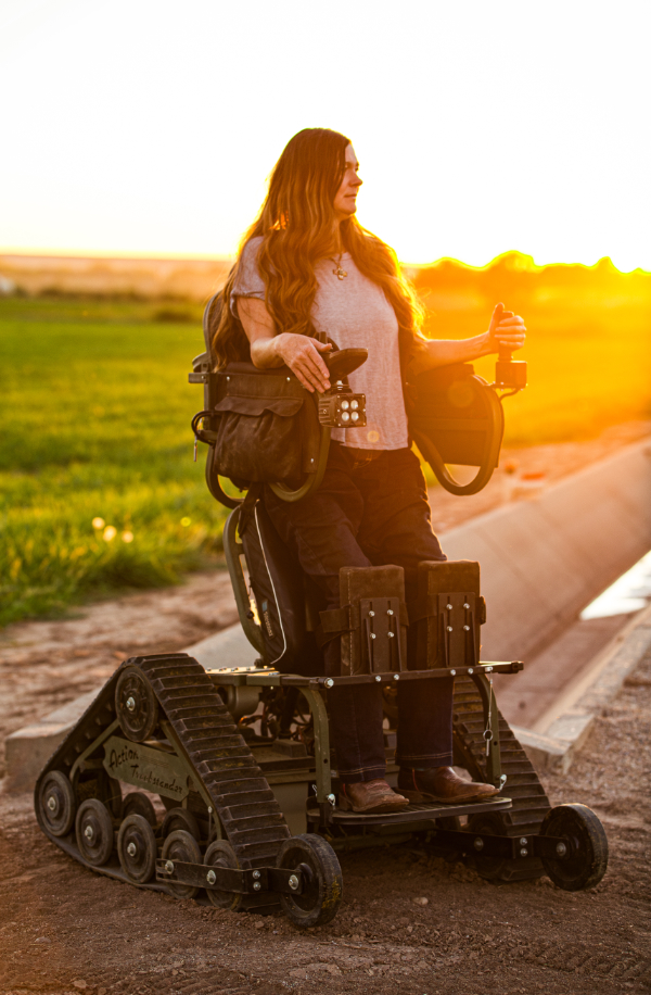 woman standing in a vertical wheelchair in a farm setting outdoors