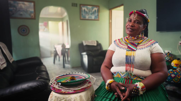 color photograph of weaving artist wearing and surrounded by her art