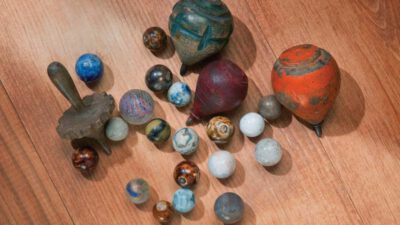 A collection of vintage marbles and wooden spinning tops scattered on a wooden surface. [gen-ai]