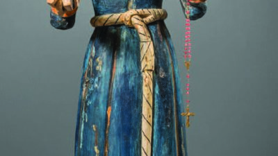 Wooden statue of a bearded man in a blue robe, holding a book in one hand and a rosary with a cross in the other, standing on a decorated base. [gen-ai]