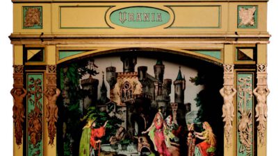 A vintage toy theater labeled Urania features painted figures on stage with a detailed backdrop of a castle and trees, surrounded by ornate green and gold decor. [gen-ai]