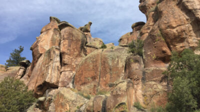 Large rock formations with rugged surfaces and sparse vegetation under a partly cloudy sky. [gen-ai]