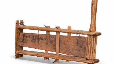 A vintage wooden washboard with a handle and wire fastenings, positioned horizontally on a white background. [gen-ai]