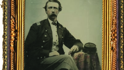 A seated man in a military uniform poses for a formal portrait, framed by an ornate gold border with detailed patterns. [gen-ai]