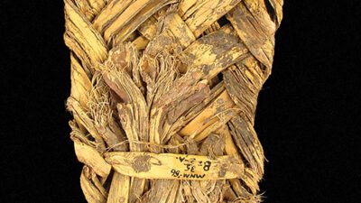 Woven sandal made from plant fibers, showing frayed edges and a checkerboard scale for size reference. [gen-ai]