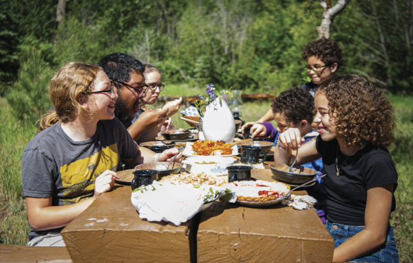 Diverse group of older children eating outdoors at a picnic table