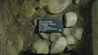Archaeological excavation showing large stones and a label identifying the site as San Miguel Church, southeast corner, dated August 9, 2013. [gen-ai]