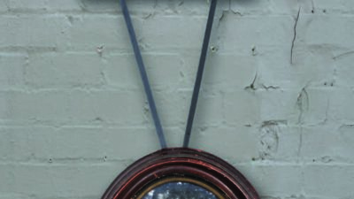 A framed black-and-white family photo hangs below a smaller square frame with an image of a tree, both connected by two black ribbons against a gray brick wall. [gen-ai]