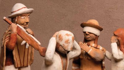 Four clay figurines in traditional attire, with one playing a flute and the others covering their ears, eyes, and mouth, set against a plain background. [gen-ai]