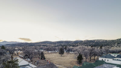 Aerial view of the Fort Stanton parade ground with the Visitor Center/ Museum on the left and the Barracks/Dining Hall on the right in the foreground. Both structures, which were originally barracks, and the parade ground date to 1855. The Sierra Blanca Mountains can be seen in the distance and are a part of the Mescalero Reservation. Photo by Tira Howard.