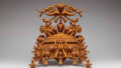Intricately beaded chair with ornate designs, including figures, patterns, and elaborate backrest details, displayed against a plain gray background. [gen-ai]