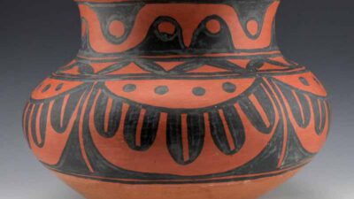 A round, reddish-brown ceramic pot with a wide rim, decorated with bold black geometric and curved patterns. [gen-ai]