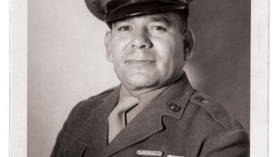 Black-and-white portrait of a man in a military uniform and cap, displaying several medals and stripes on his jacket, facing the camera with a neutral expression. [gen-ai]
