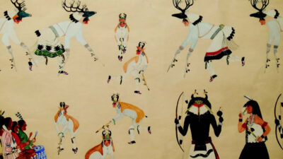 A group of Indigenous dancers in traditional regalia perform ceremonial dances, with musicians seated to the left holding instruments and singing. [gen-ai]