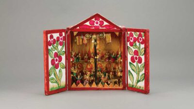 A painted wooden box with open doors displays a diorama of small, colorful figurines arranged in two rows, framed by floral designs on the doors. [gen-ai]