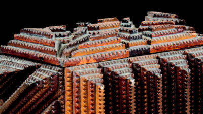 Close-up of a dark brown, geometric, wooden box featuring rows of raised triangular patterns in a symmetrical, stepped arrangement. [gen-ai]