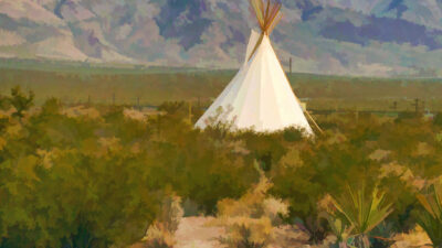 A white teepee stands in a desert landscape with green shrubs, set against distant mountains under a blue sky. [gen-ai]