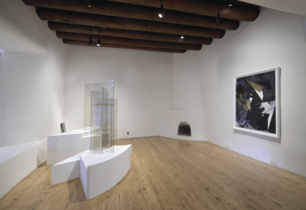 Contemporary art gallery with wooden floors, sculptural glass pieces on white plinths, a large abstract painting on the wall, and exposed wooden ceiling beams.