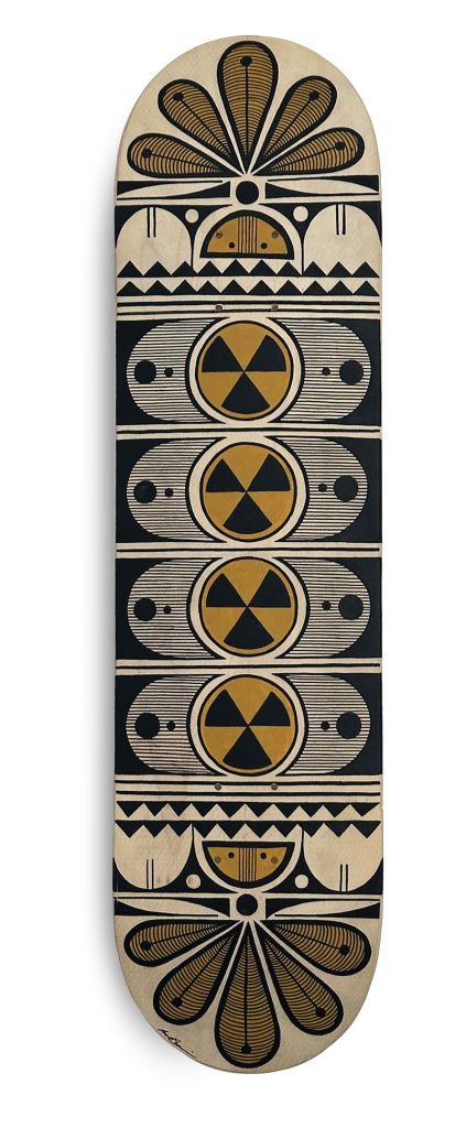 A skateboard deck with a geometric abstract design in black, gold, and beige, featuring repeating patterns of circles, triangles, and symmetrical shapes arranged vertically.